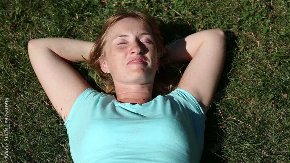 Girl lying on the grass, her hands behind her head
Girl lying on the grass, her hands behind her head