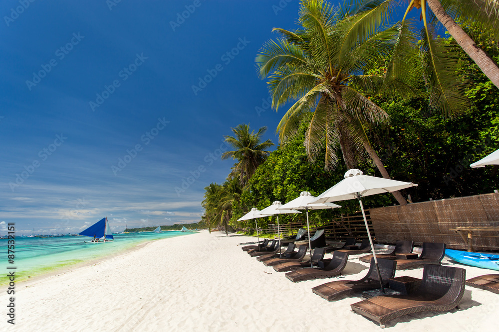 Sun umbrellas and beach chairs on tropical coastline