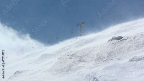 Strong wind carries snowflakes along the slope in the ski resort photo