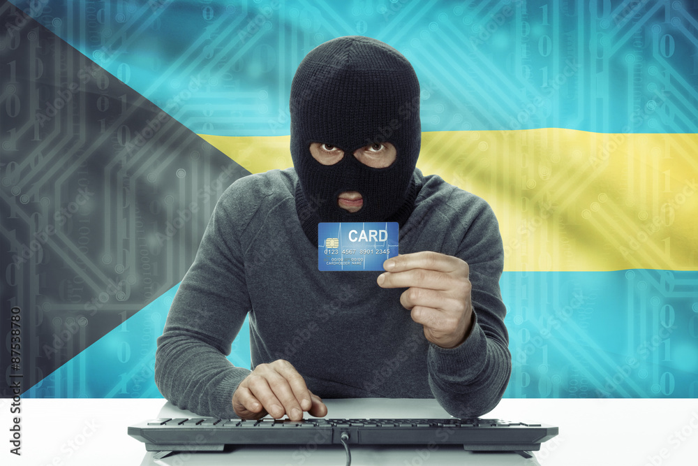 Dark-skinned hacker with flag on background holding credit card - Bahamas Dark-skinned hacker with flag on background holding credit card - Bahamas