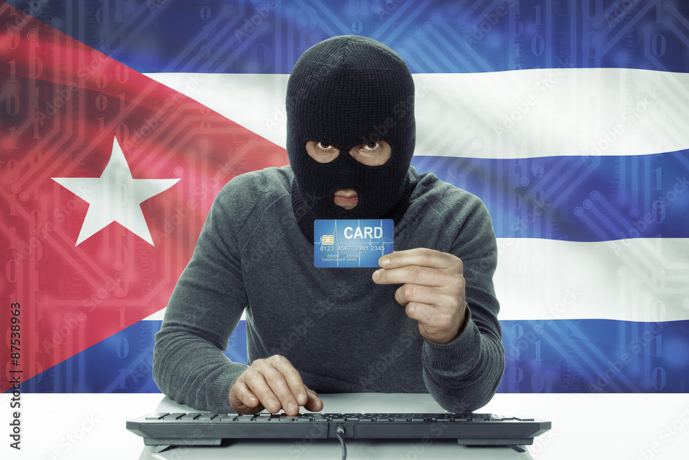 Dark-skinned hacker with flag on background holding credit card - Cuba Dark-skinned hacker with flag on background holding credit card - Cuba