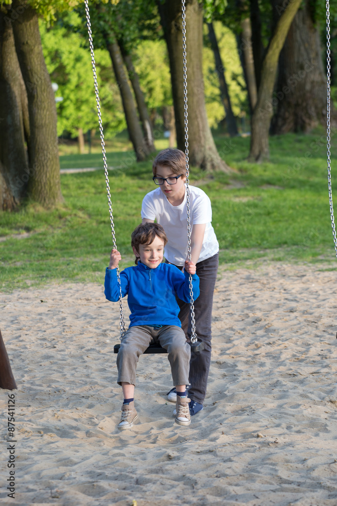 Fun on the swing, the boys together on the playground Fun on the swing, the boys together on the playground