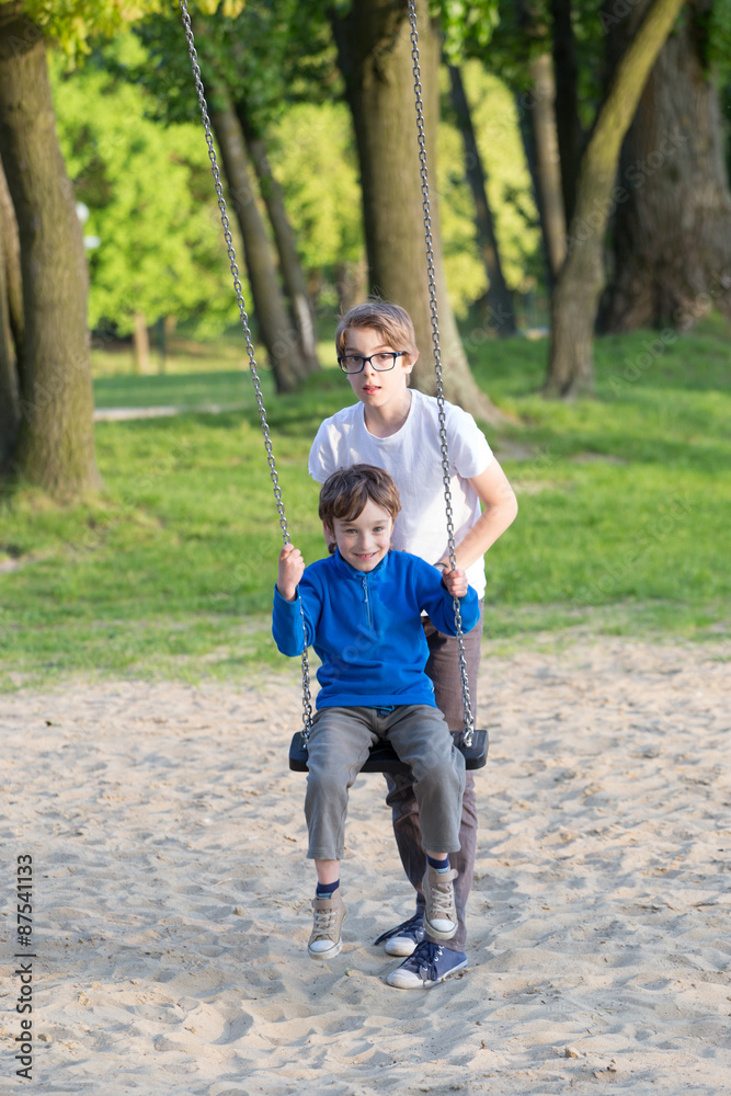 Fototapeta premium Fun on the swing, the boys together on the playground 