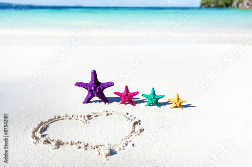 Heart on beach with color starfishes