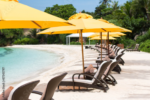 Sun umbrellas and beach chairs on tropical beach