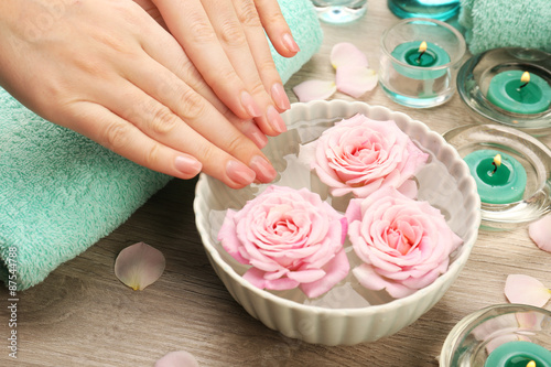 Female hands and bowl of spa water with flowers  closeup