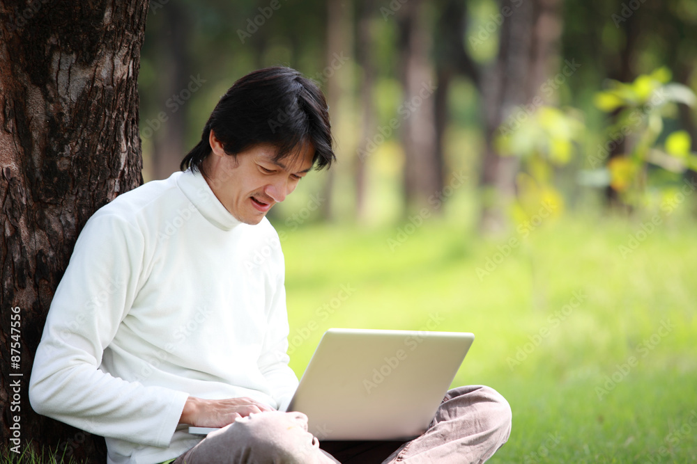 Young man using his laptop on the grass Young man using his laptop on the grass