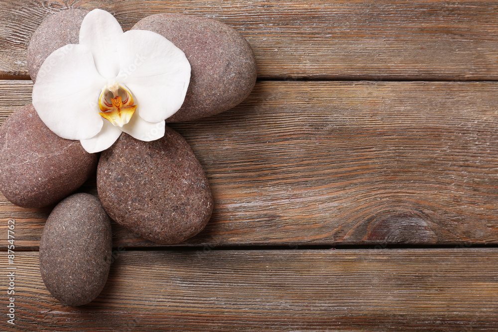 Naklejka premium Spa stones and orchid flower on wooden background