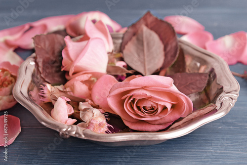 Beautiful pink roses in metal plate on wooden table, closeup