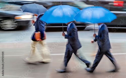 business people walking in the street on a rainy day motion blur
