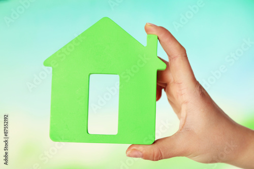 Female hand with model of house on blurred background
