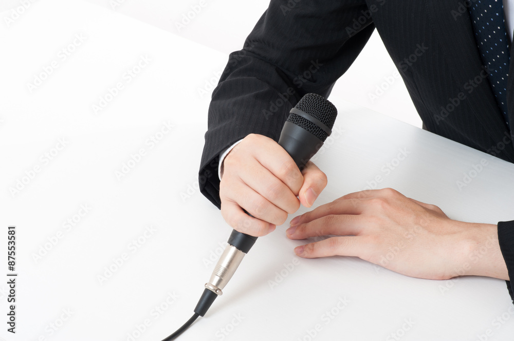 記者会見でマイクを使って謝罪している役員