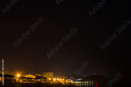 The stars over the night sea city on the beach. © scadidi