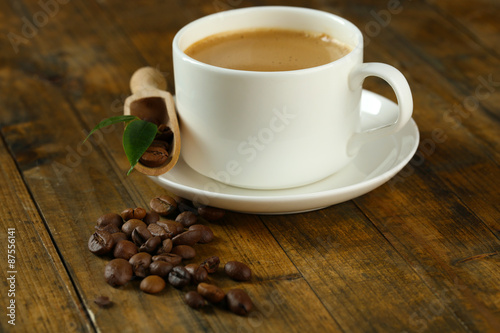 Cup of coffee with beans on table close up