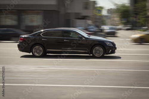 Black lexus fast driving on a city street.