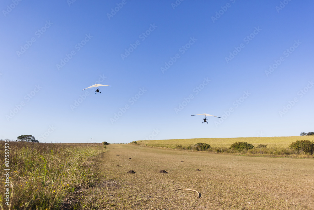 Flying microlight aircraft planes take-off on rural grass airstrip. Flying microlight aircraft planes take-off on rural grass airstrip.