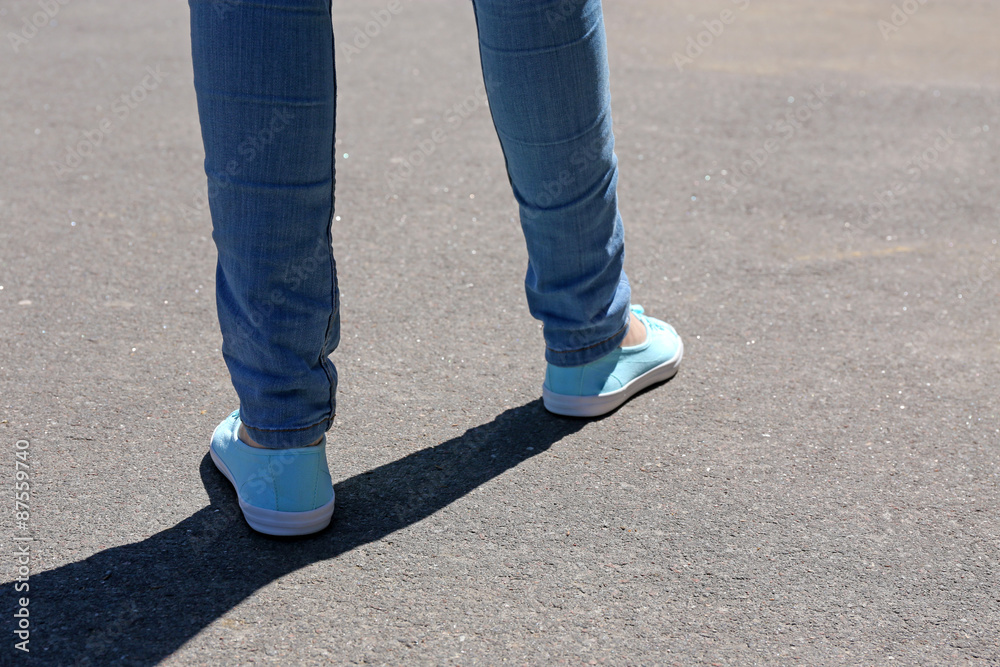 Female feet on gray asphalt background Female feet on gray asphalt background