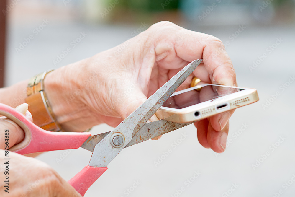 The old man's hand holding scissors and cut mobile phone. The old man's hand holding scissors and cut mobile phone.
