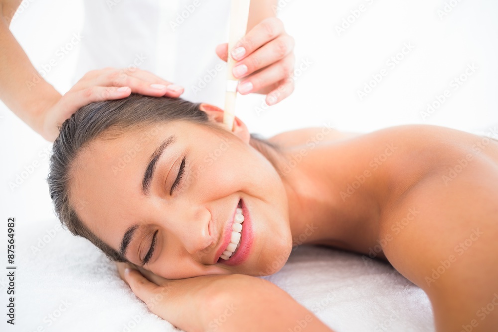 Beautiful woman receiving ear candle treatment at spa center Beautiful woman receiving ear candle treatment at spa center