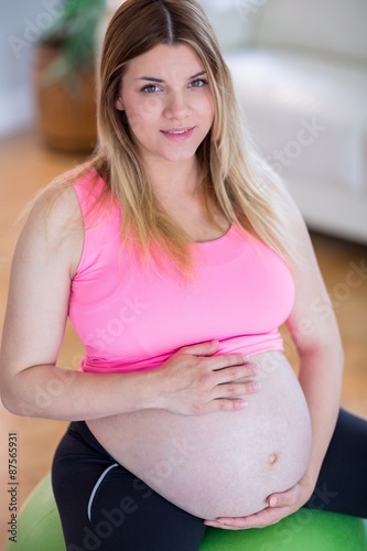 Free Download Pregnant woman touching her belly on exercise ball - GFXLoad