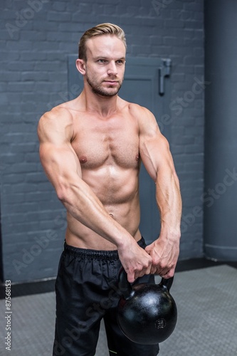 Muscular man lifting a kettlebell