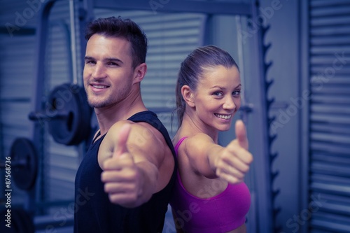 Smiling muscular couple gesturing thumbs up 