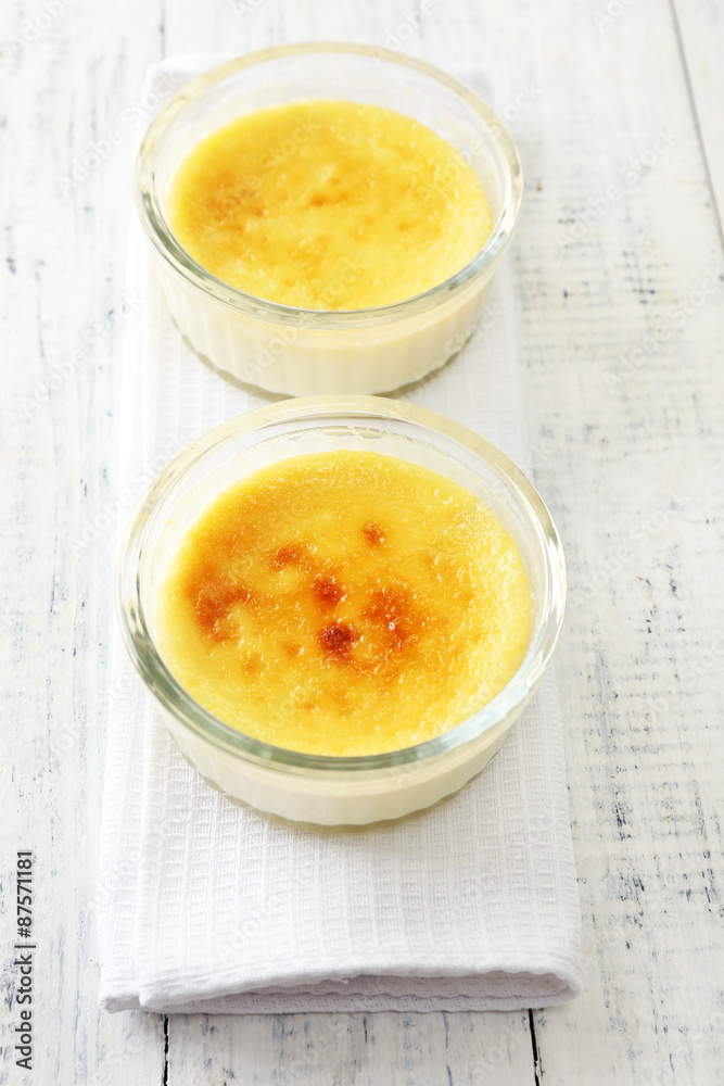 Creme brulee dessert on napkin, on color wooden background Creme brulee dessert on napkin, on color wooden background