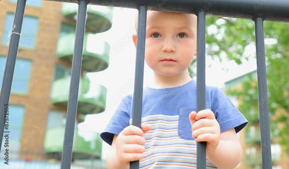 Obraz premium Portrait of a sad child behind the bars