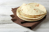 Stack of homemade whole wheat flour tortilla on napkin, on wooden background