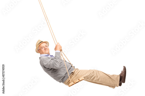 Carefree senior man swinging on a wooden swing