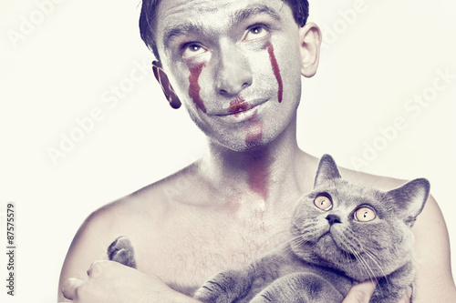 Man with silver makeup on his face and cat in hands