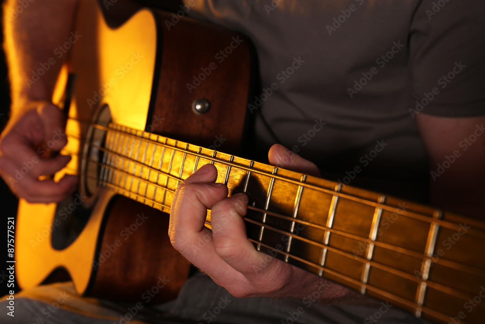 Fototapeta premium Young man playing on acoustic guitar close up