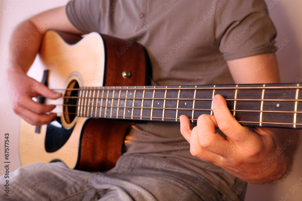 Fototapeta premium Young man playing on acoustic guitar close up