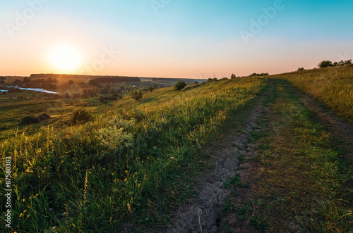 Field with country road and beautiful sunset