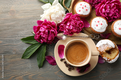 Composition with cup of coffee, muffins and peony flowers on wooden background