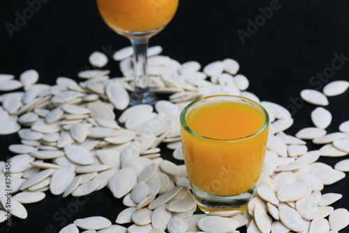 Pumpkin seeds and juice on a black background