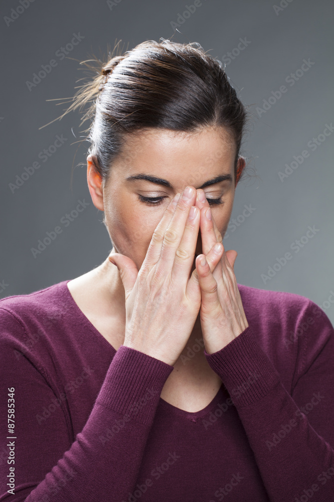 beautiful young woman with brown hair hiding her face in both hands looking down for sadness beautiful young woman with brown hair hiding her face in both hands looking down for sadness