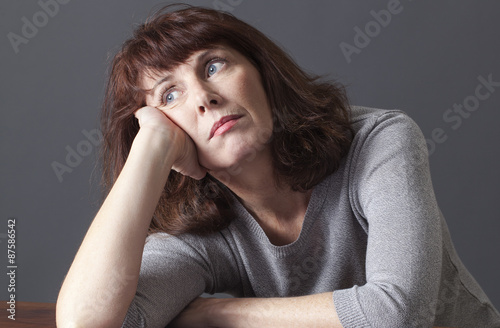 Obraz na plátně depressed mature woman with brown hair and grey winter sweater leaning her face