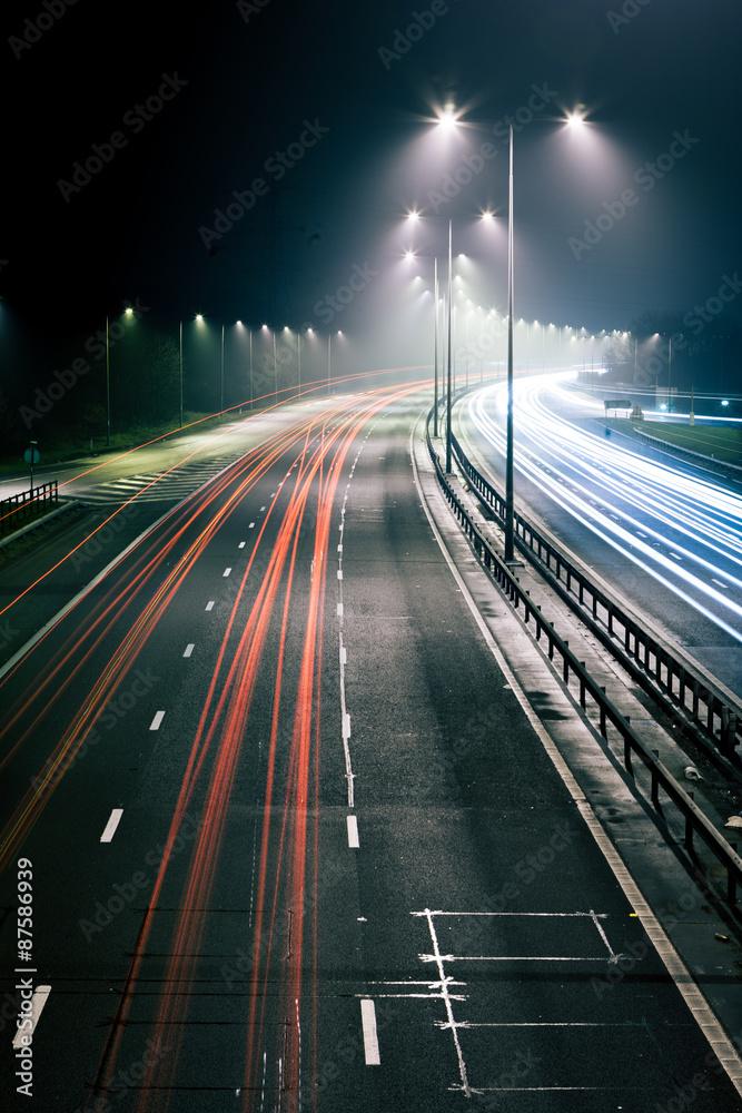 Traffic light trails. Long exposure of a UK motorway at night time with traffic trails illustrating cars driving on the left.