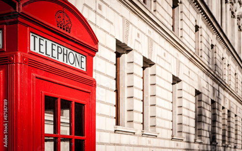 London telephone box. Traditional old-style UK red phone box set against a beige government building in central London.