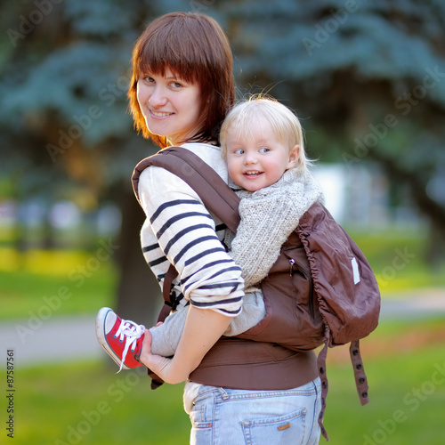 Young mother with her toddler child in a baby carrier 