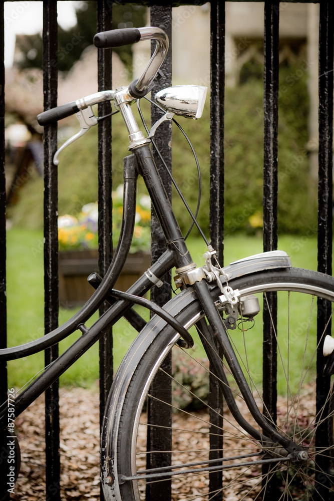 Locked bicycle. An old fashioned bicycle with a retro dynamo locked to some railings by a Cambridge University college. Locked bicycle. An old fashioned bicycle with a retro dynamo locked to some railings by a Cambridge University college.