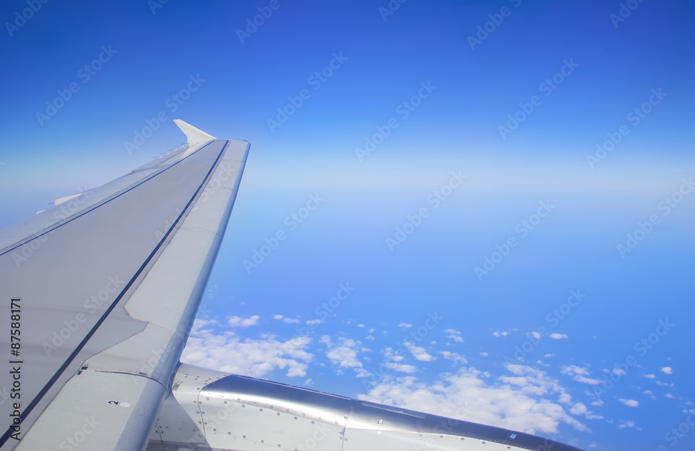 Wing of an airplane flying above the clouds. people looks at the sky from the window of the plane, using airtransport to travel. Wing of an airplane flying above the clouds. people looks at the sky from the window of the plane, using airtransport to travel.