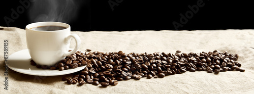 Panoramic view of frothy coffee cup with beans on fabric flax
