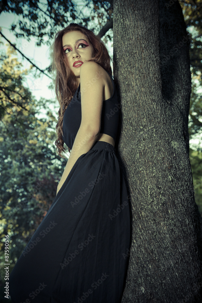 Romantic, beautiful woman in a forest, redhead with long hair Romantic, beautiful woman in a forest, redhead with long hair