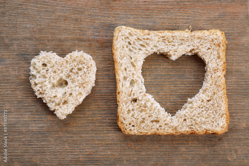 Bread slice with cut in shape of heart on wooden background