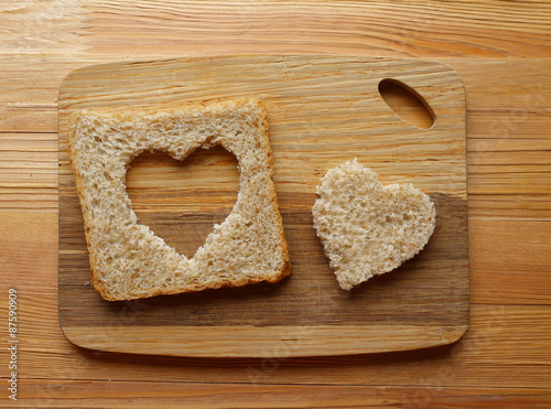 Bread slice with cut in shape of heart on wooden background