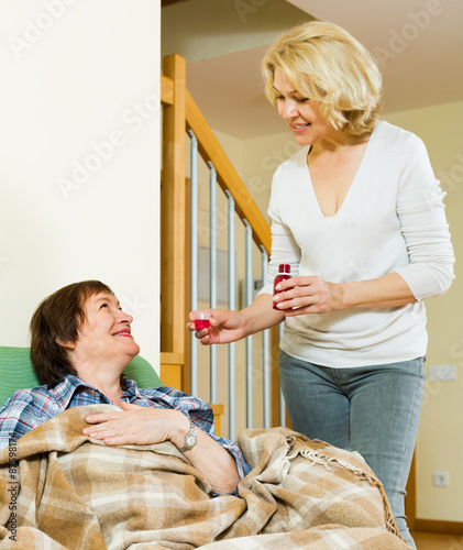 Mature woman visiting  sick elderly friend and giving her a linc photo