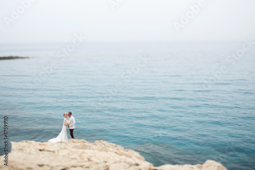 beautiful  gorgeous blonde bride  and stylish groom on rocks  on the background of a sea  wedding ceremony  on cyprus.