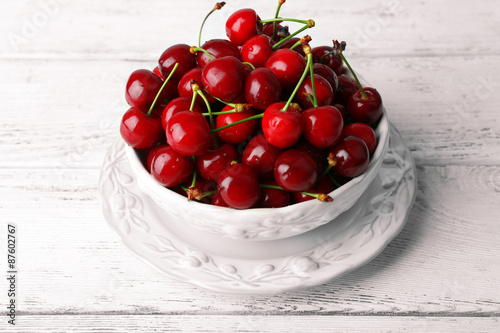 Sweet cherries in bowl on wooden table close up